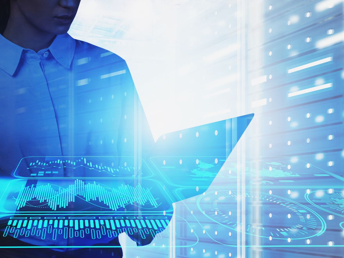 Image of woman standing in front of GPUs in a data center holding a laptop.